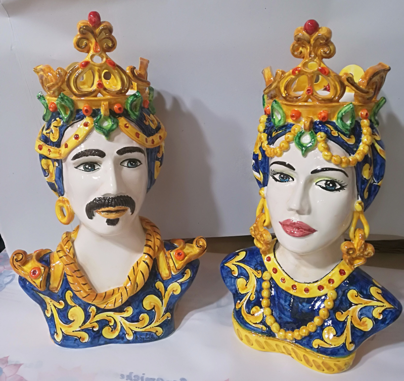 Due busti in ceramica siciliana: un uomo e una donna con corone, decorati con dettagli blu e oro.