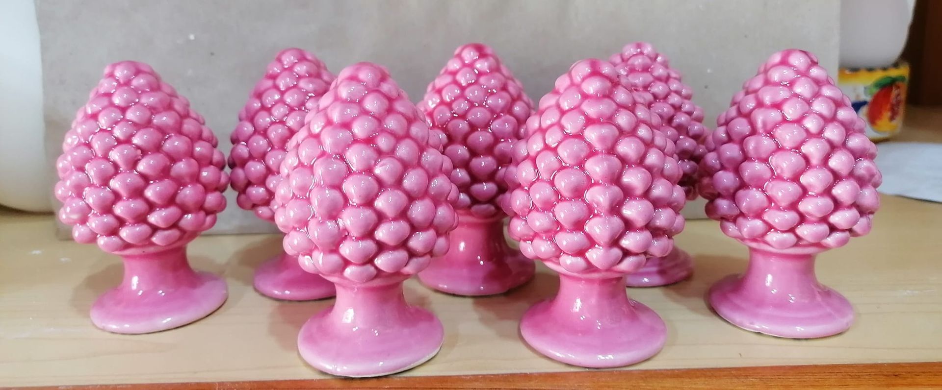 Statuine di ananas in ceramica rosa disposte su una superficie di legno.