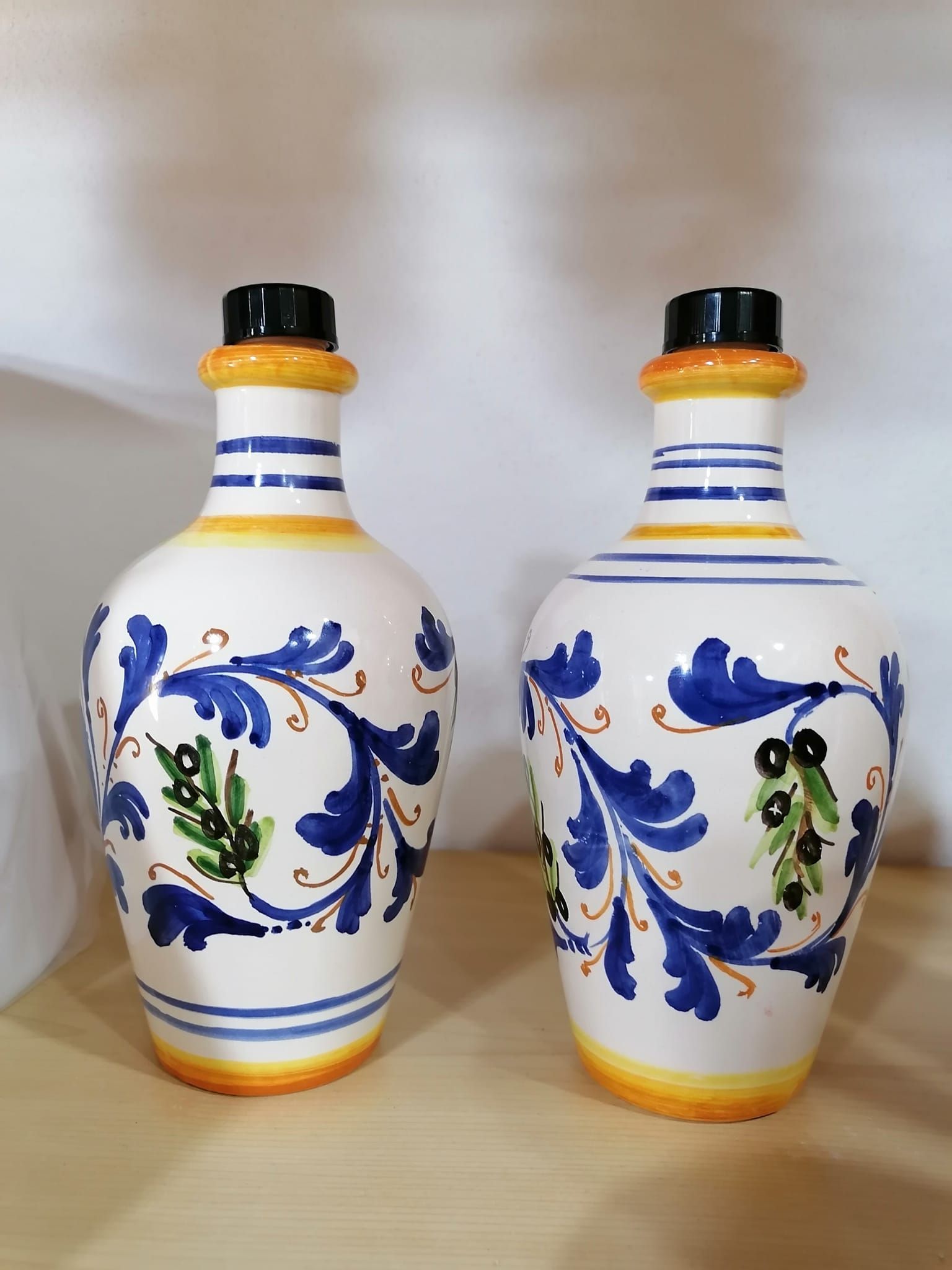 Due bottiglie in ceramica bianca con motivi floreali blu e dettagli gialli e neri.