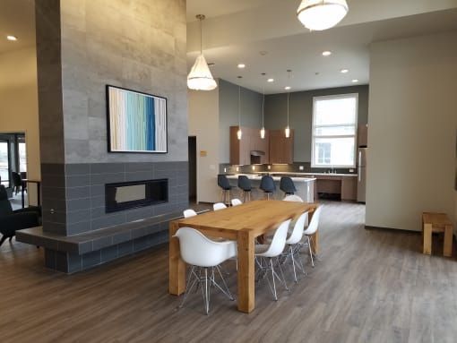 Modern open-plan space with fireplace, dining table, kitchen, and neutral color palette.