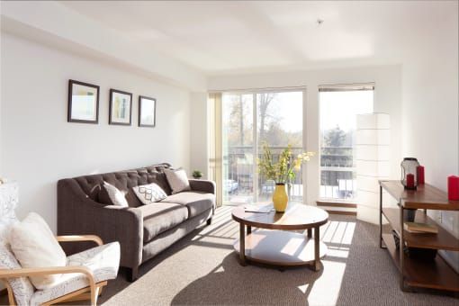 Living room with grey sofa, round coffee table, and large windows.