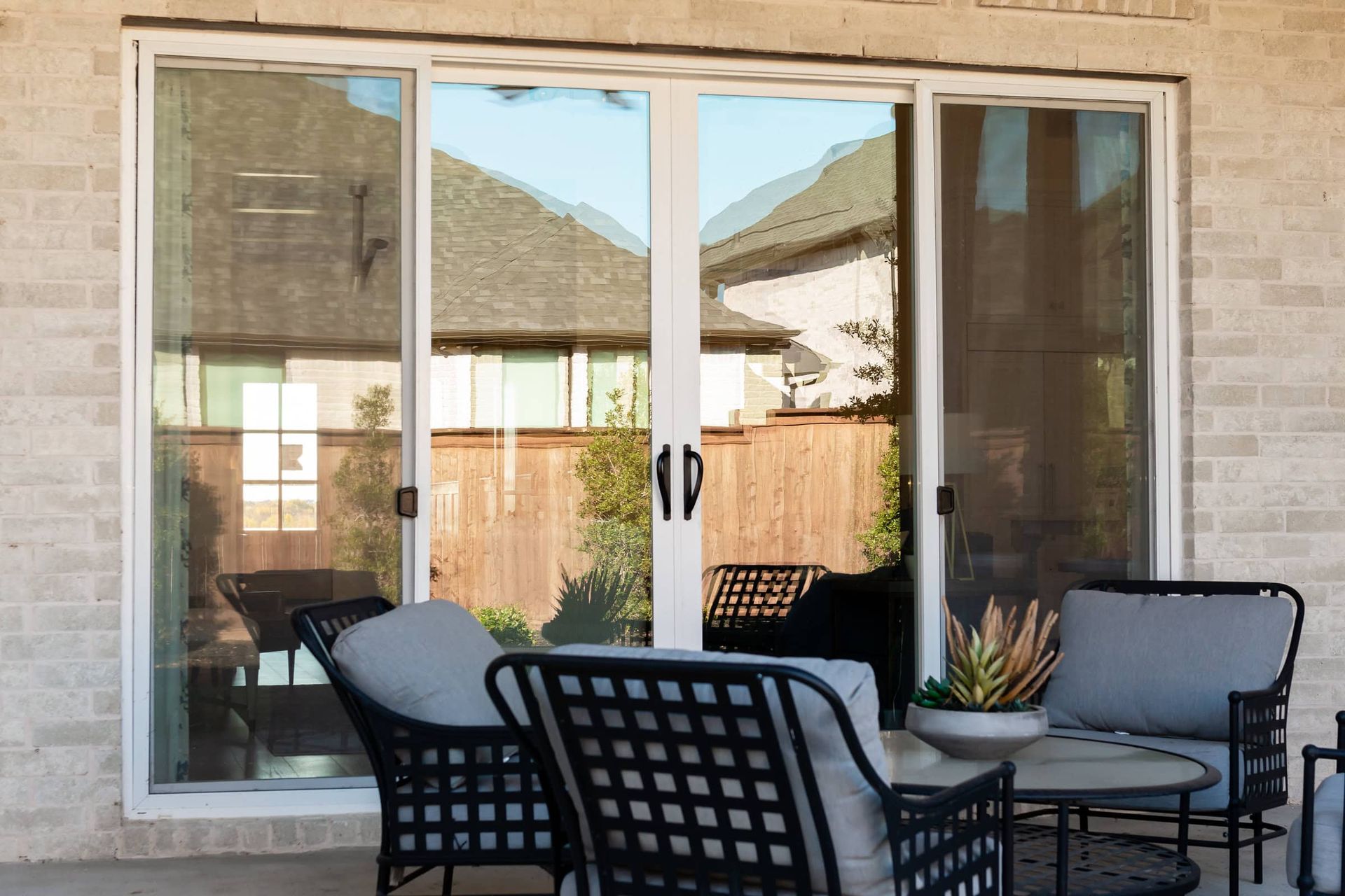 A patio with a couch , chairs and a table in front of a sliding glass door.