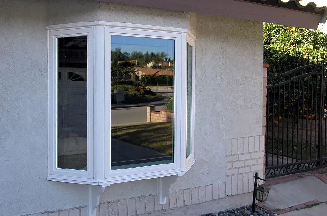 A white bay window is on the side of a house.