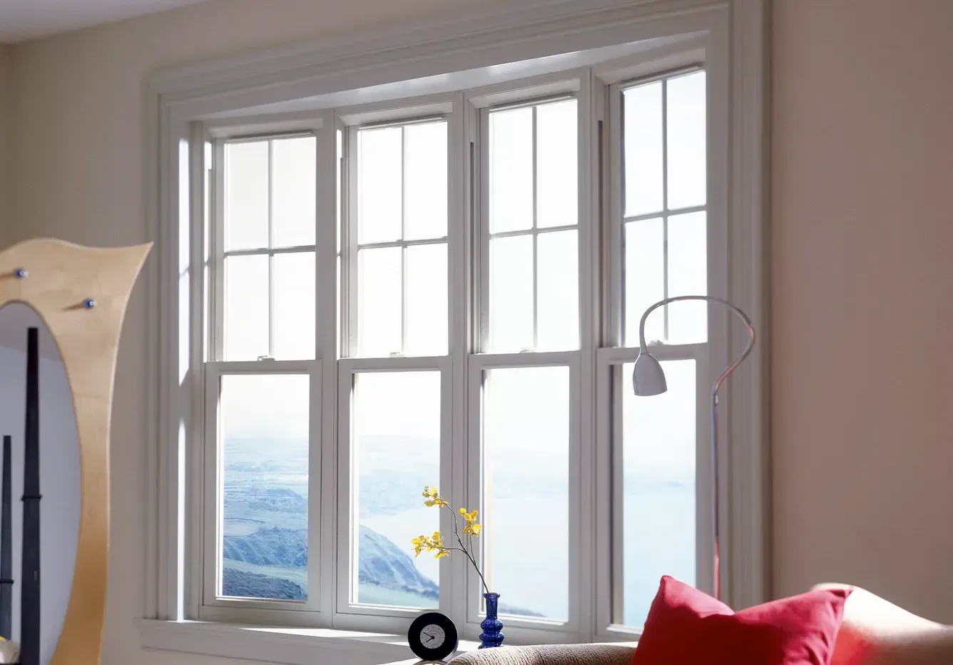 A living room with a large window and a red pillow on the couch.