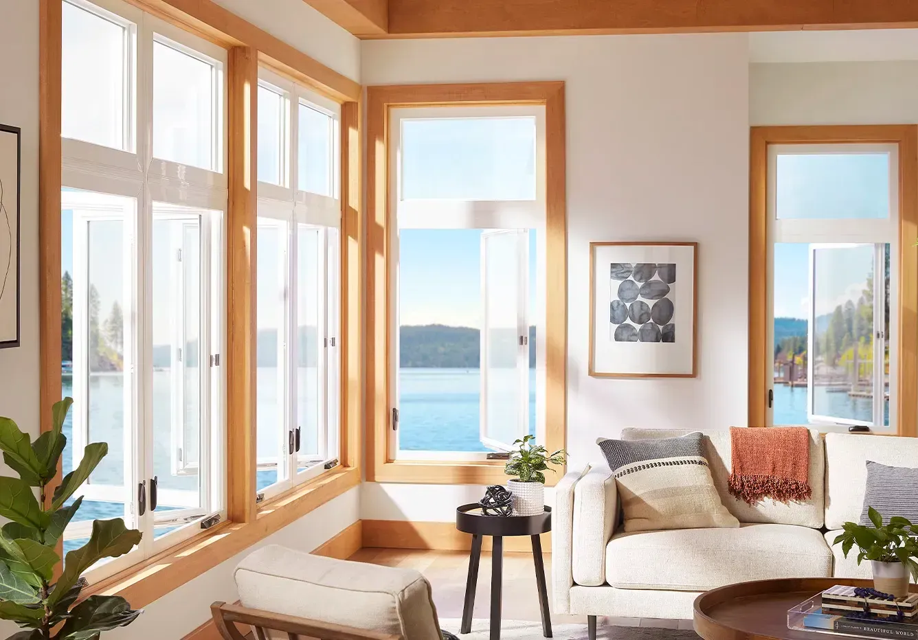 A living room with a couch , chair , table and lots of windows.