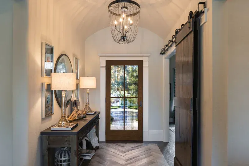 A hallway with a sliding barn door and a chandelier hanging from the ceiling.