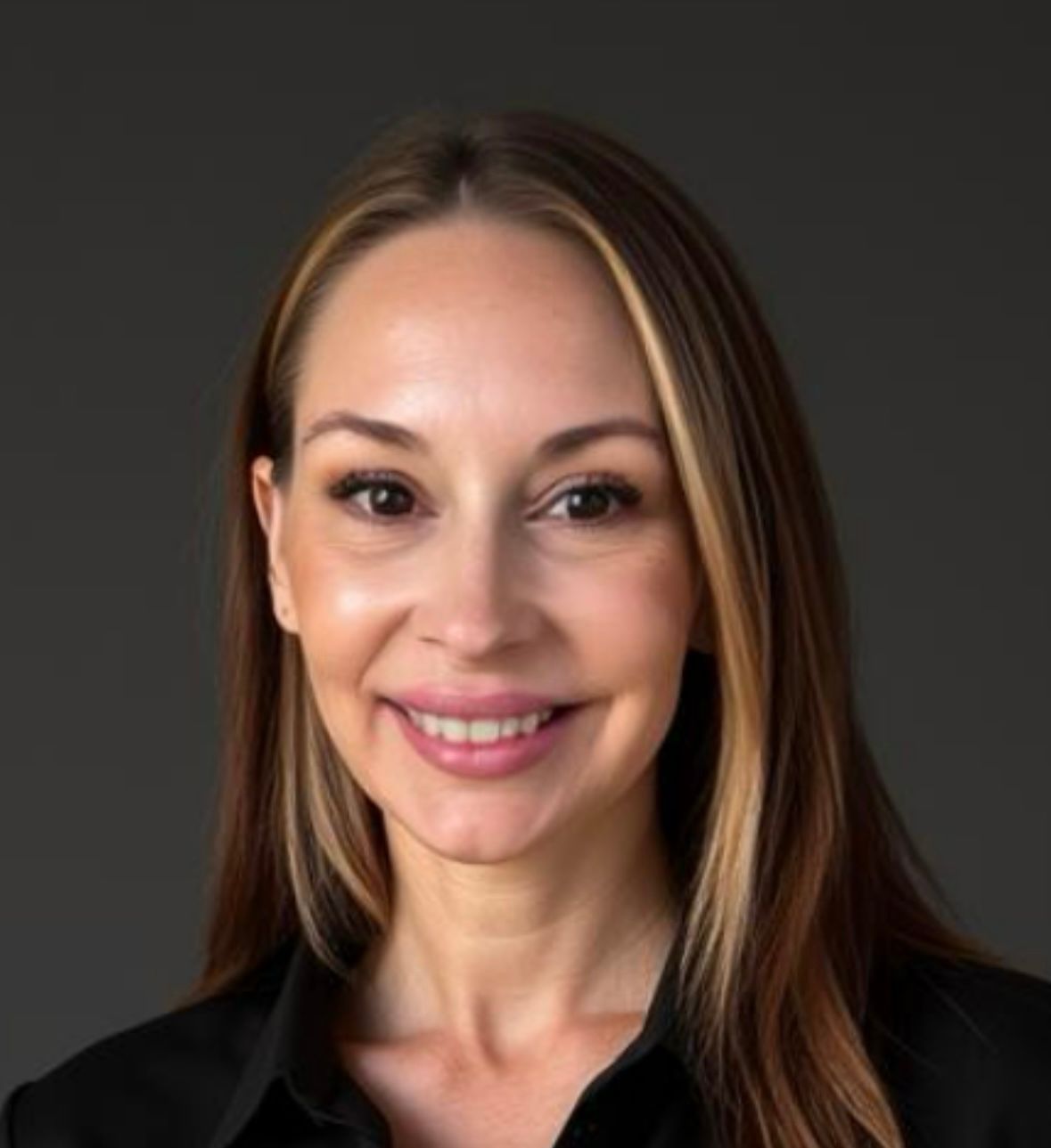 A woman with long brown hair is smiling and wearing a black shirt