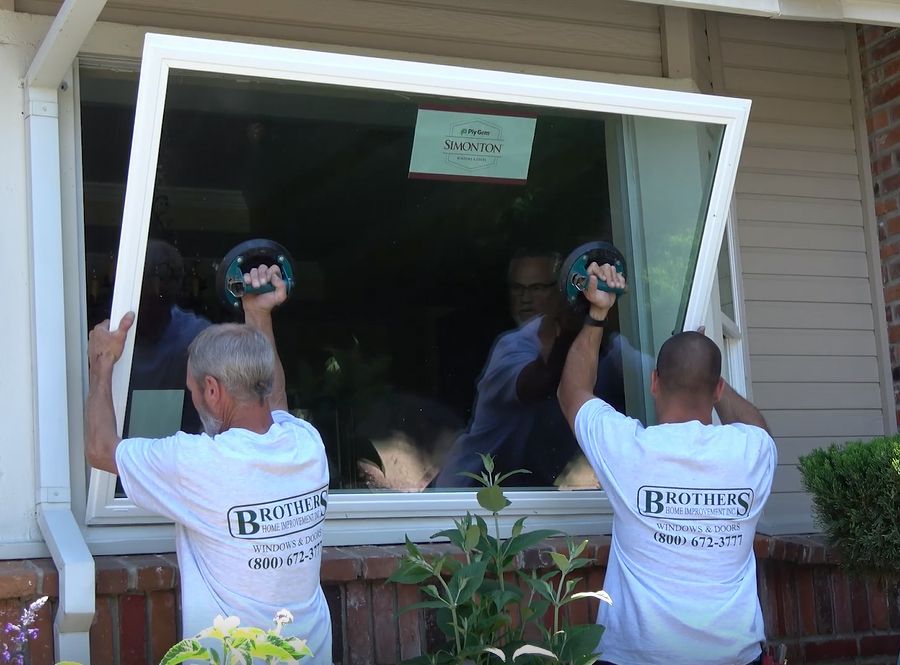Two men are installing a window in a house.