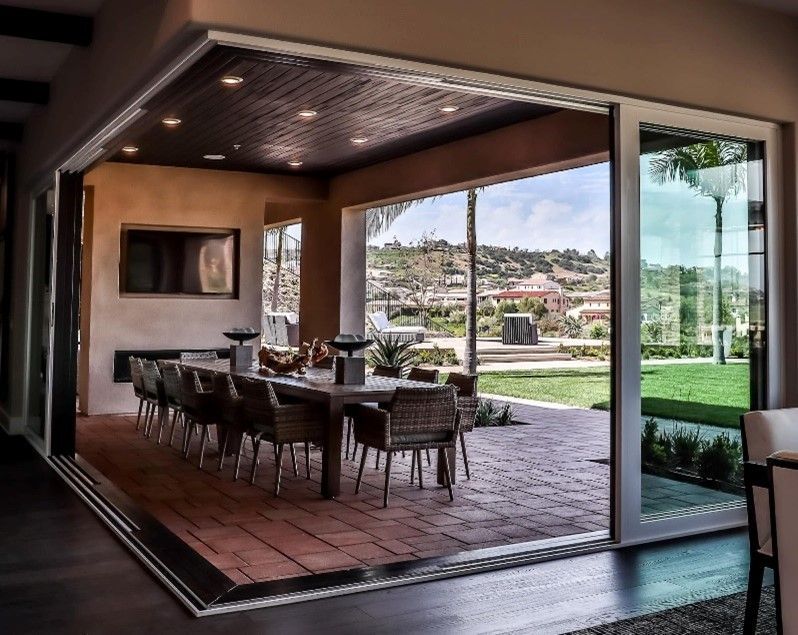 A dining room with a table and chairs and sliding glass doors