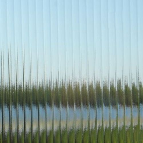 A reflection of trees in a glass window with a lake in the background.