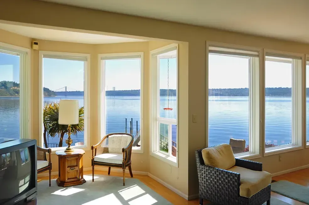 A living room with a couch , chair , table and lots of windows.