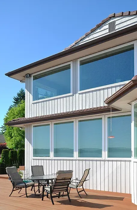 A white house with a large deck and a table and chairs on it