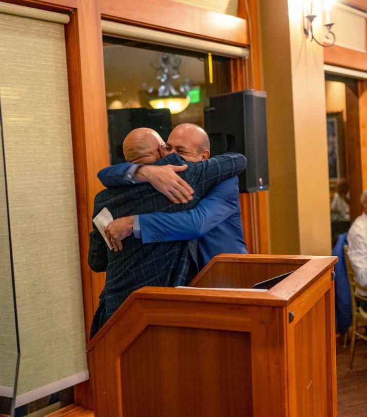 Two men hugging each other in front of a podium.
