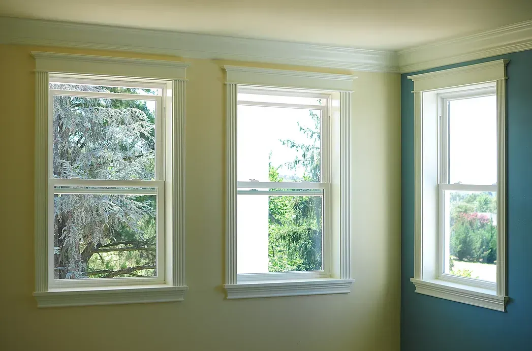 A room with two windows and a blue wall