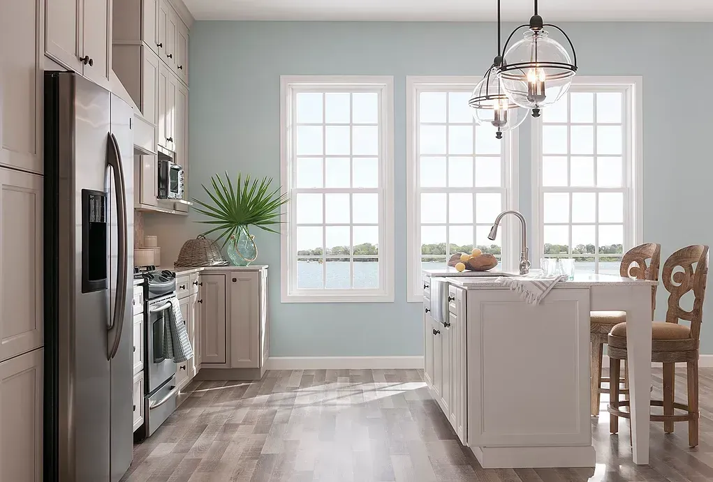 A kitchen with blue walls , white cabinets , stainless steel appliances , and a large island.