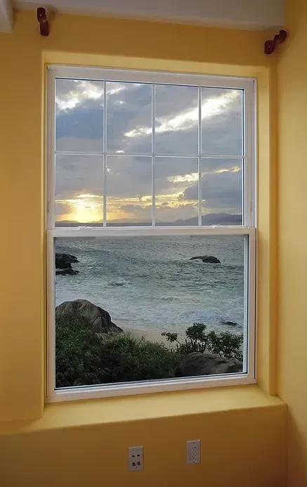 A window with a view of the ocean and sunset