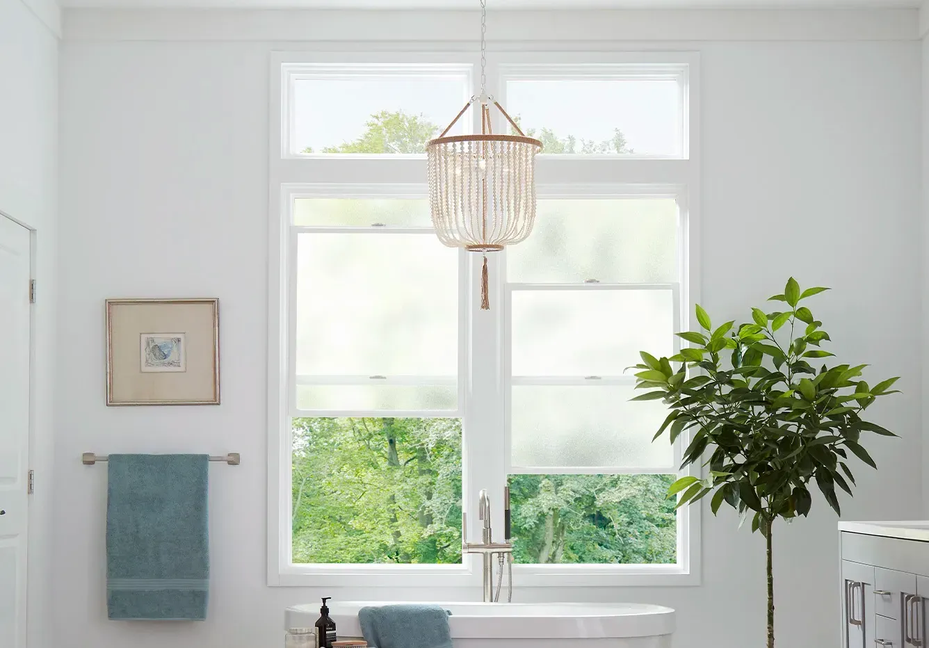A bathroom with a tub and a window with a chandelier hanging from the ceiling.