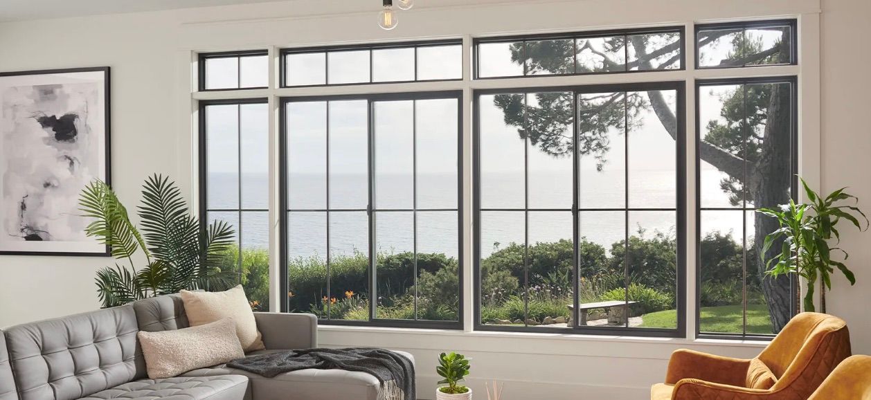 A living room with a couch , chair , and large windows.