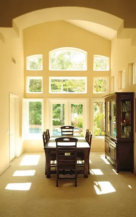 A dining room with a table and chairs and lots of windows