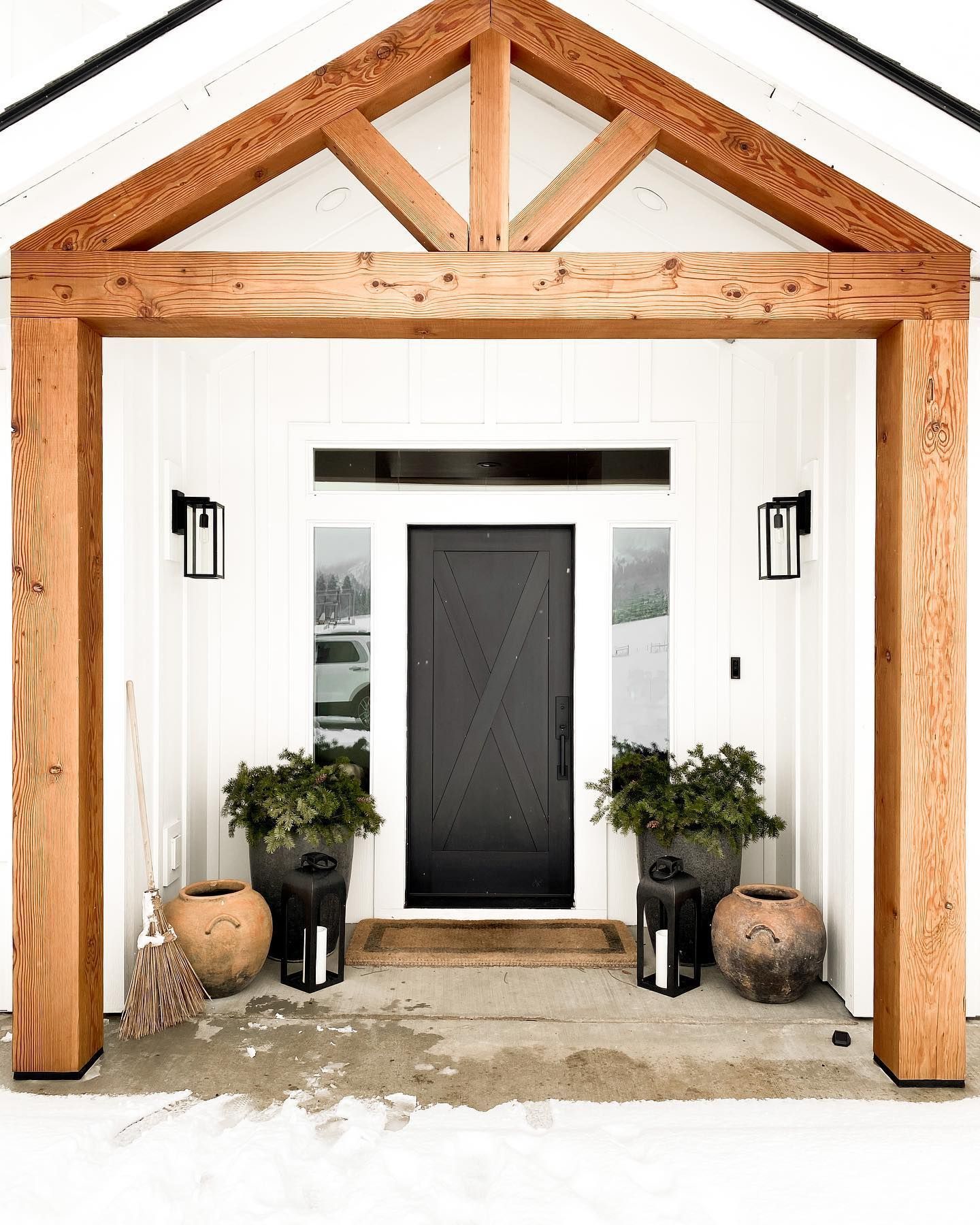 A white house with a black door and a wooden porch.