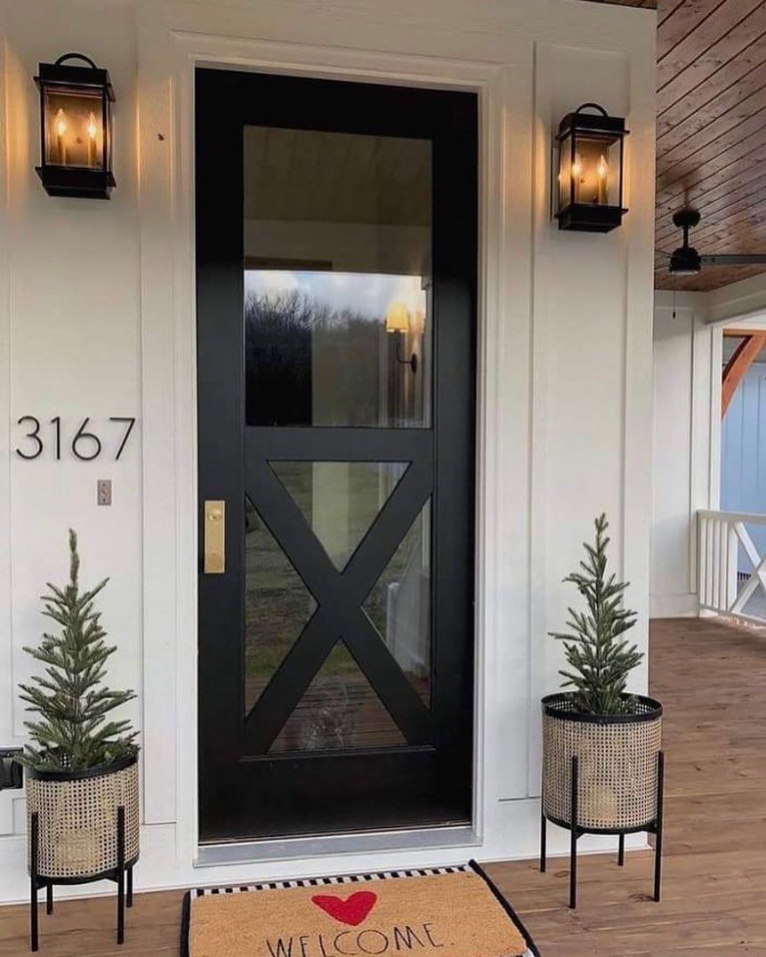 A white house with a black door and a wooden porch.