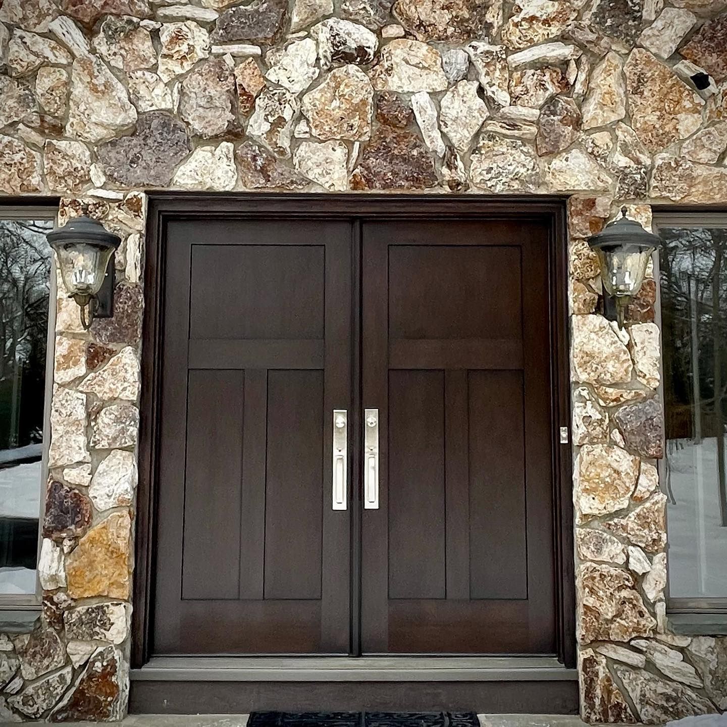 A stone wall with a wooden door and two windows