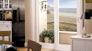 A kitchen with a sliding glass door leading to a balcony with a view of the ocean.