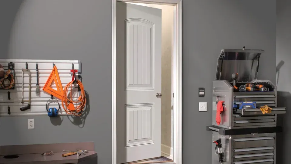 A garage with a door open and a toolbox.