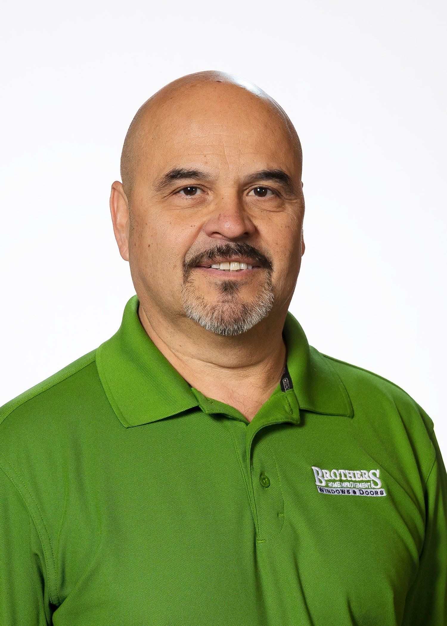 A bald man with a beard is wearing a green shirt.