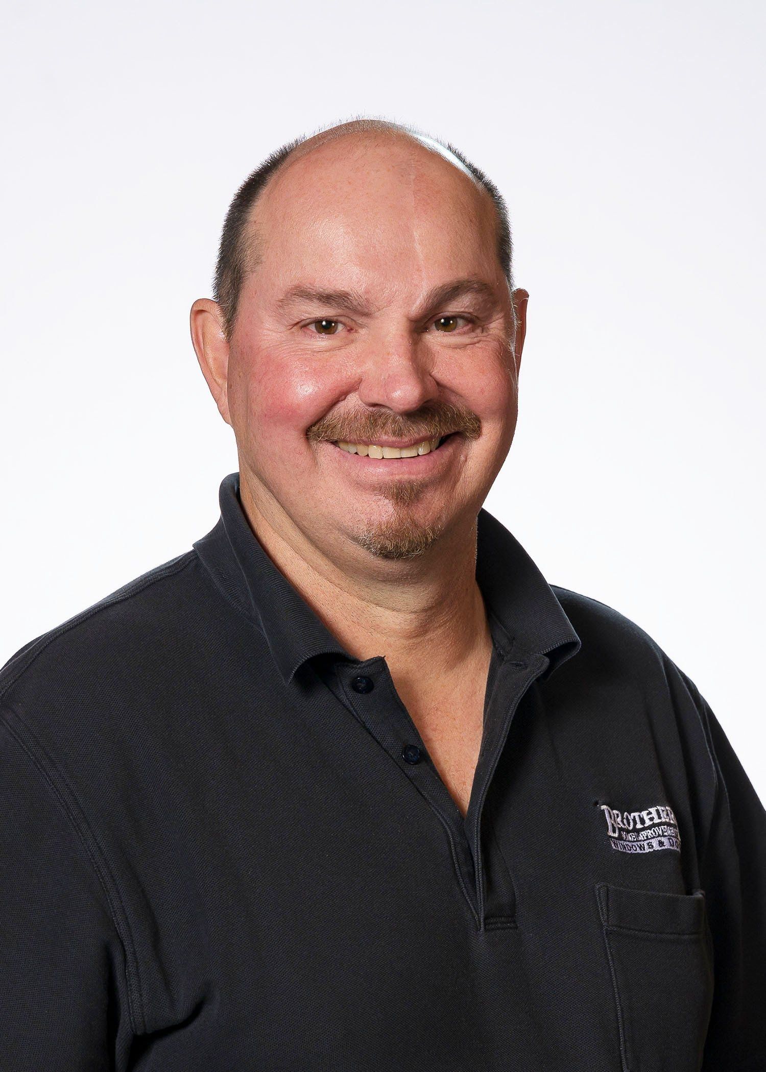 A man in a black shirt is smiling for the camera.
