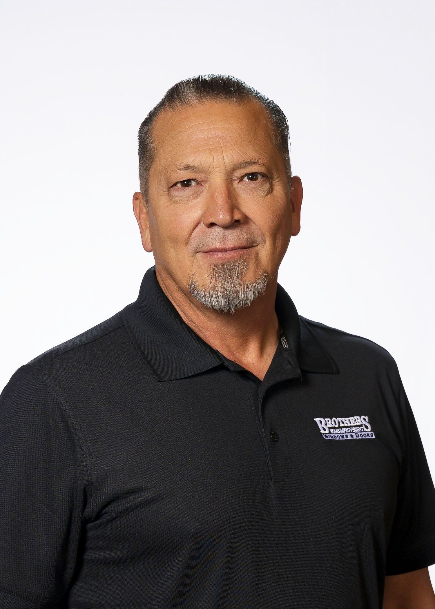 A man with a beard is wearing a black polo shirt.