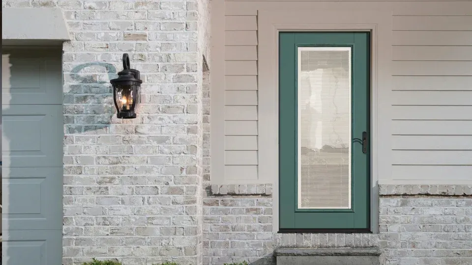 A white brick house with a green door and a garage door.
