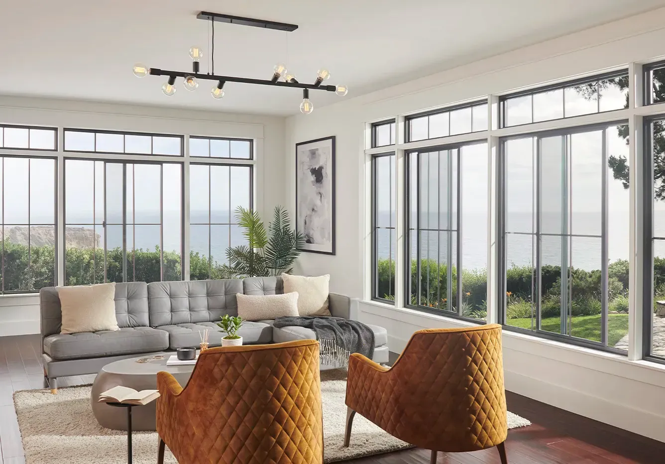 A living room with a couch , chairs , and lots of windows.