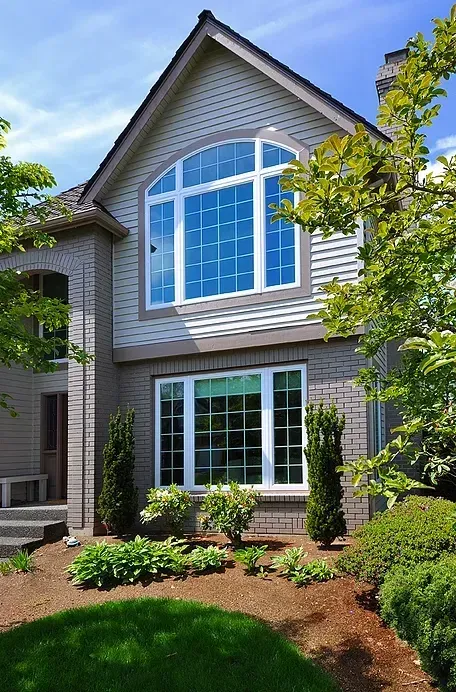 A large house with lots of windows and trees in front of it