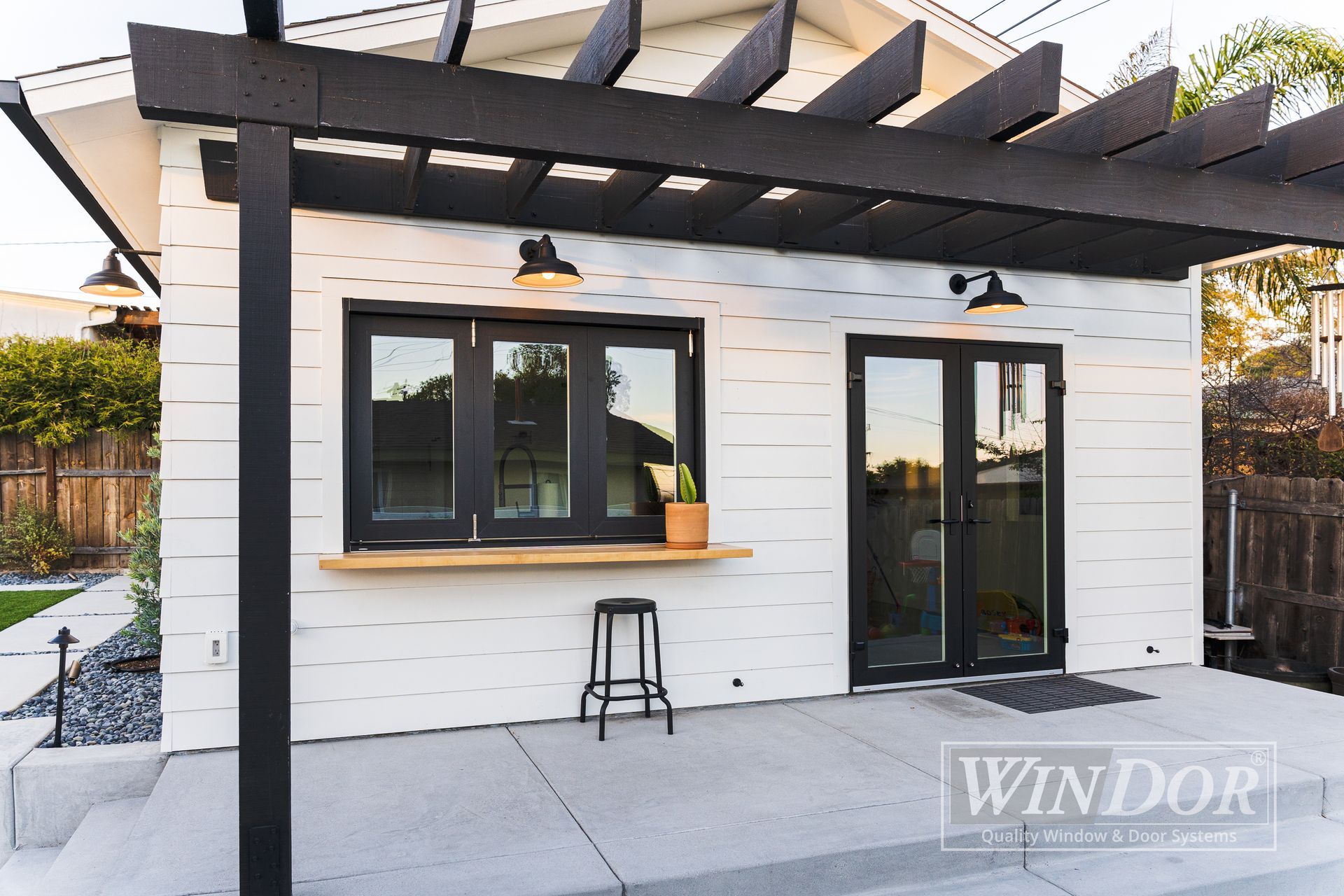 A white house with a black pergola on top of it