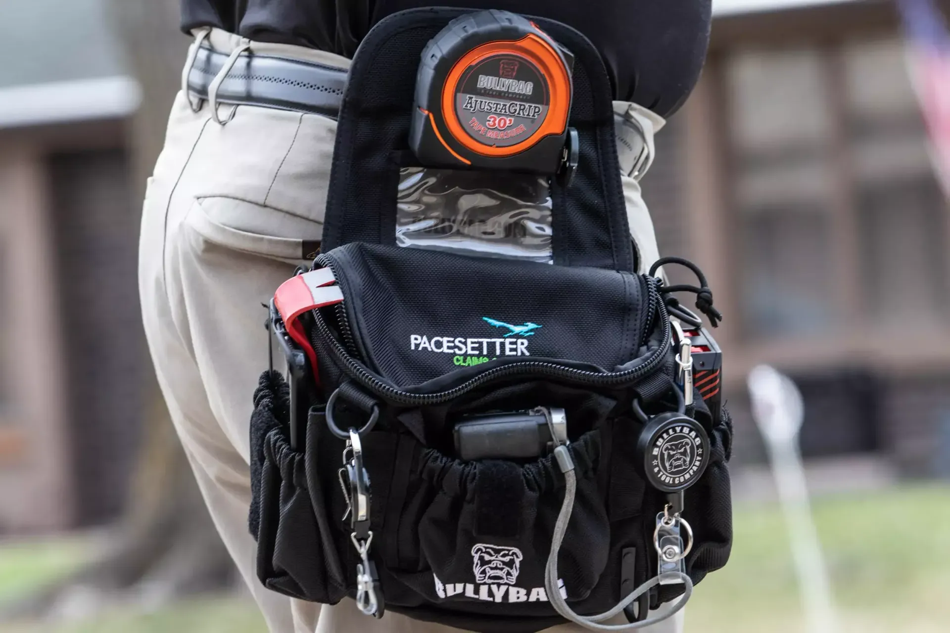 Person wearing a black pack on their waist; bag has a timer and various pockets with tools.