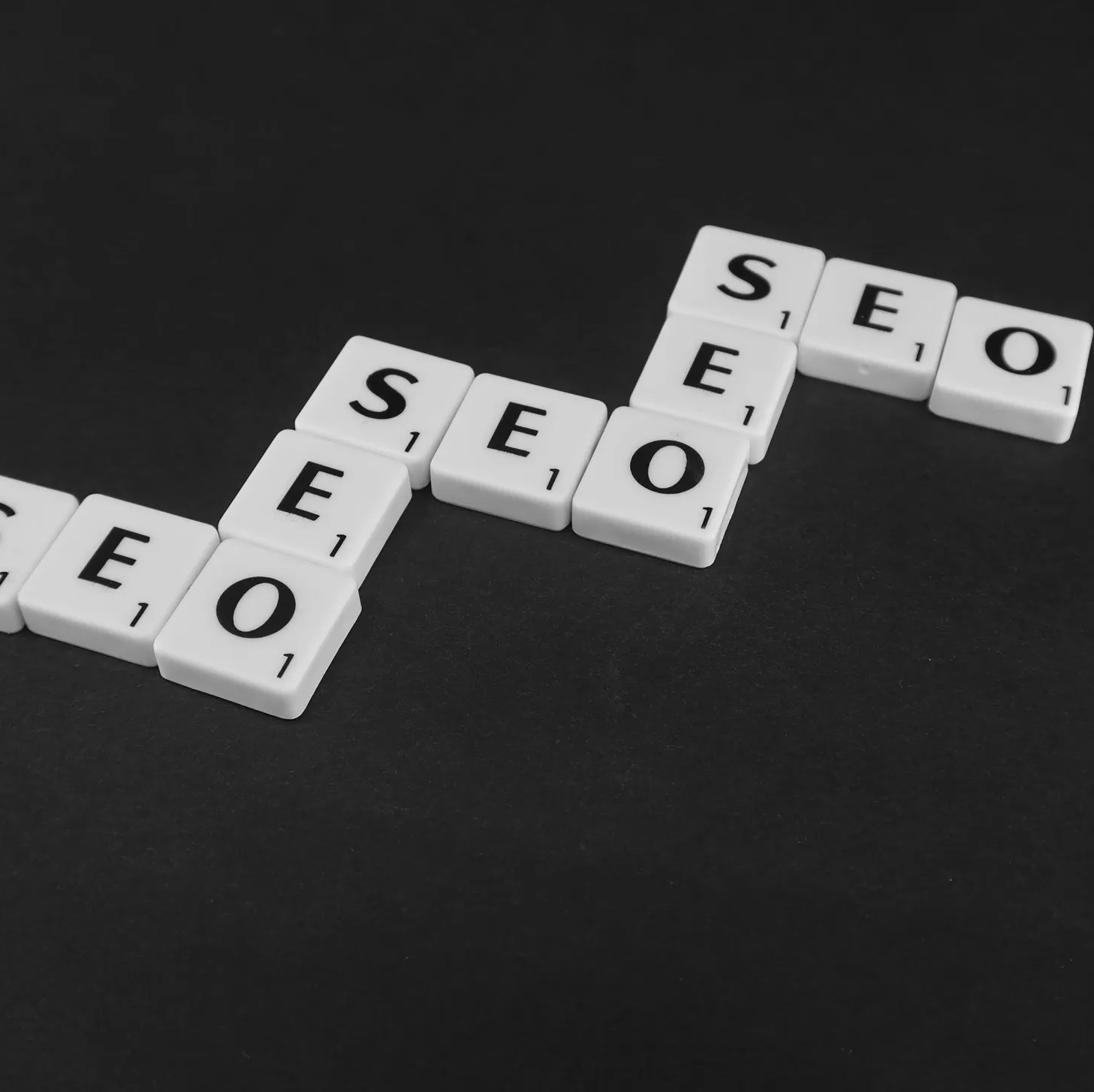 Scrabble tiles spelling out the word seo on a black background