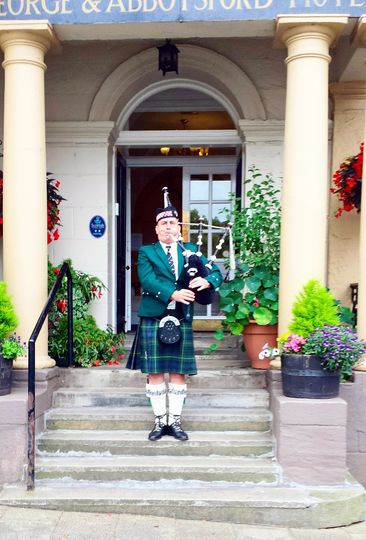 A traditional bagpipe player outside the George & Abbotsford Hotel