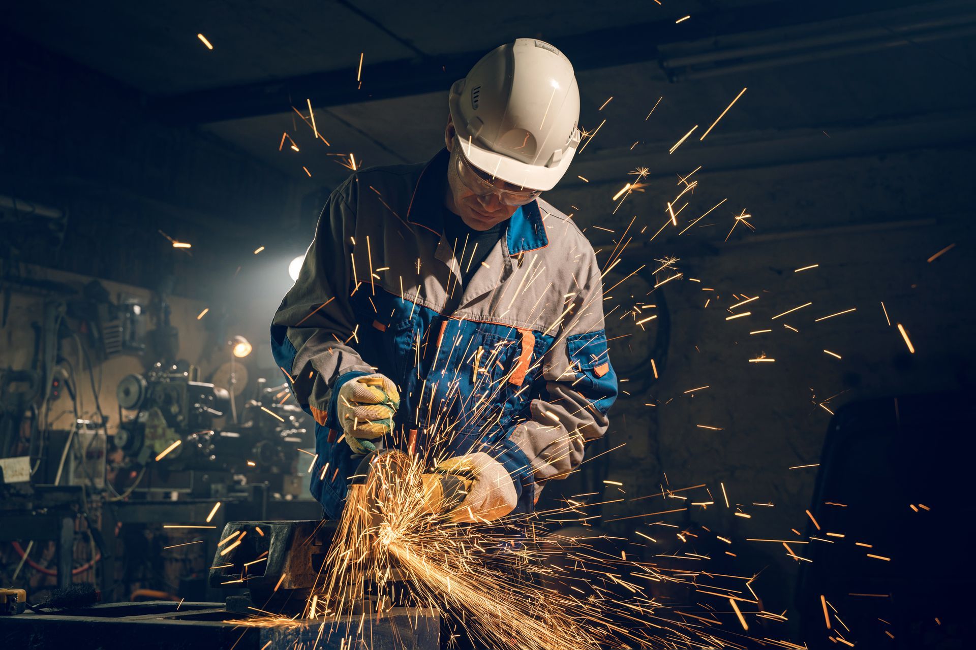 A man is grinding a piece of metal with a grinder in a factory.