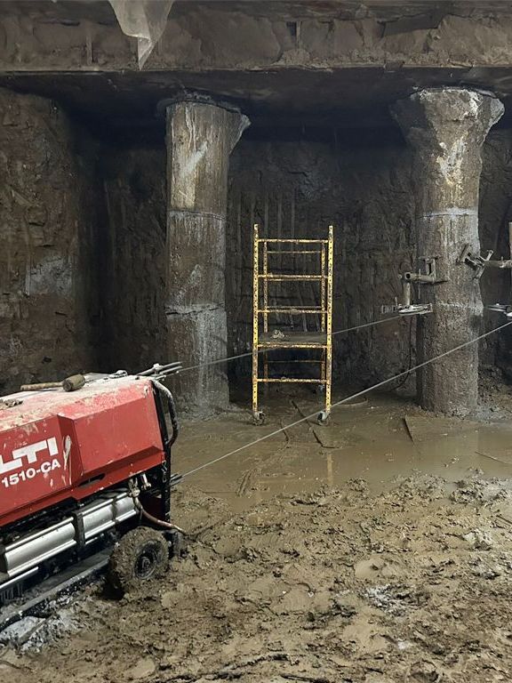 A red machine is sitting in the middle of a muddy room.
