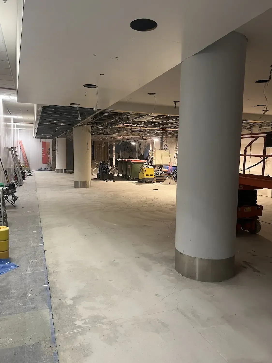 A large empty room with columns and a lift in the middle of it.