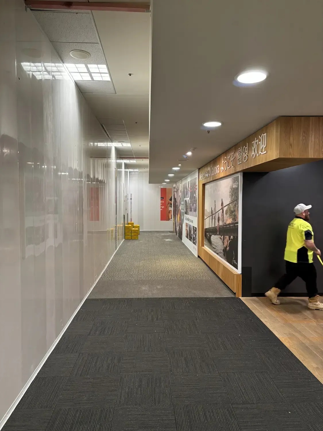 A man in a yellow shirt is walking down a long hallway.