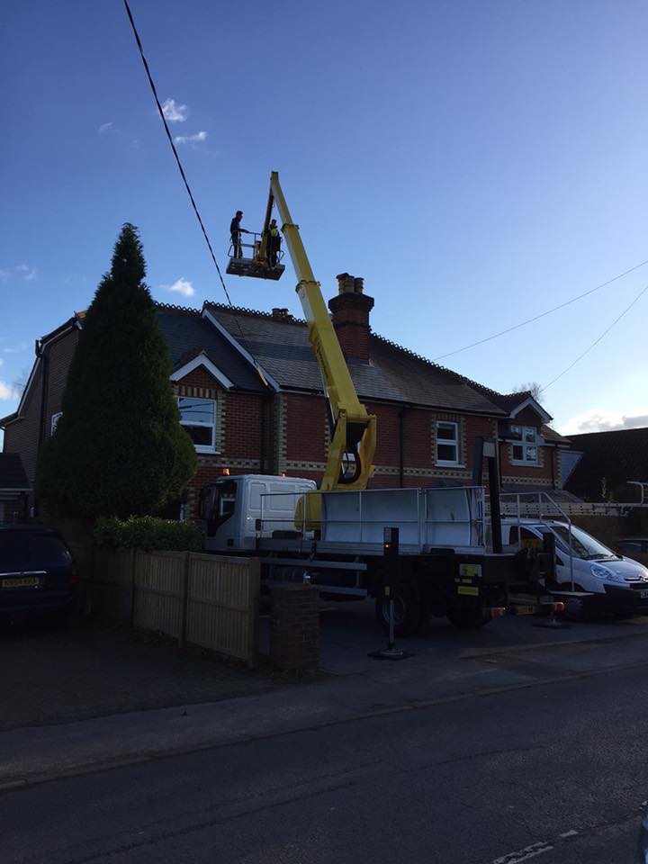 Cherry picker accessing overhead cables above residential house