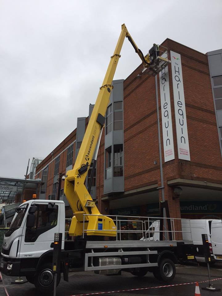 Installing large sign on side of commercial building on cherry picker