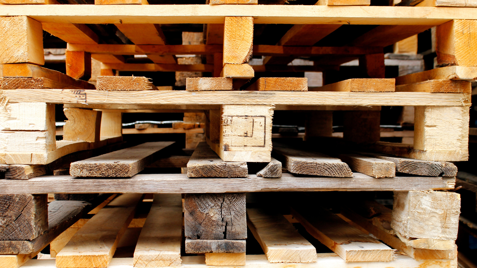 A pile of wooden pallets are stacked on top of each other.