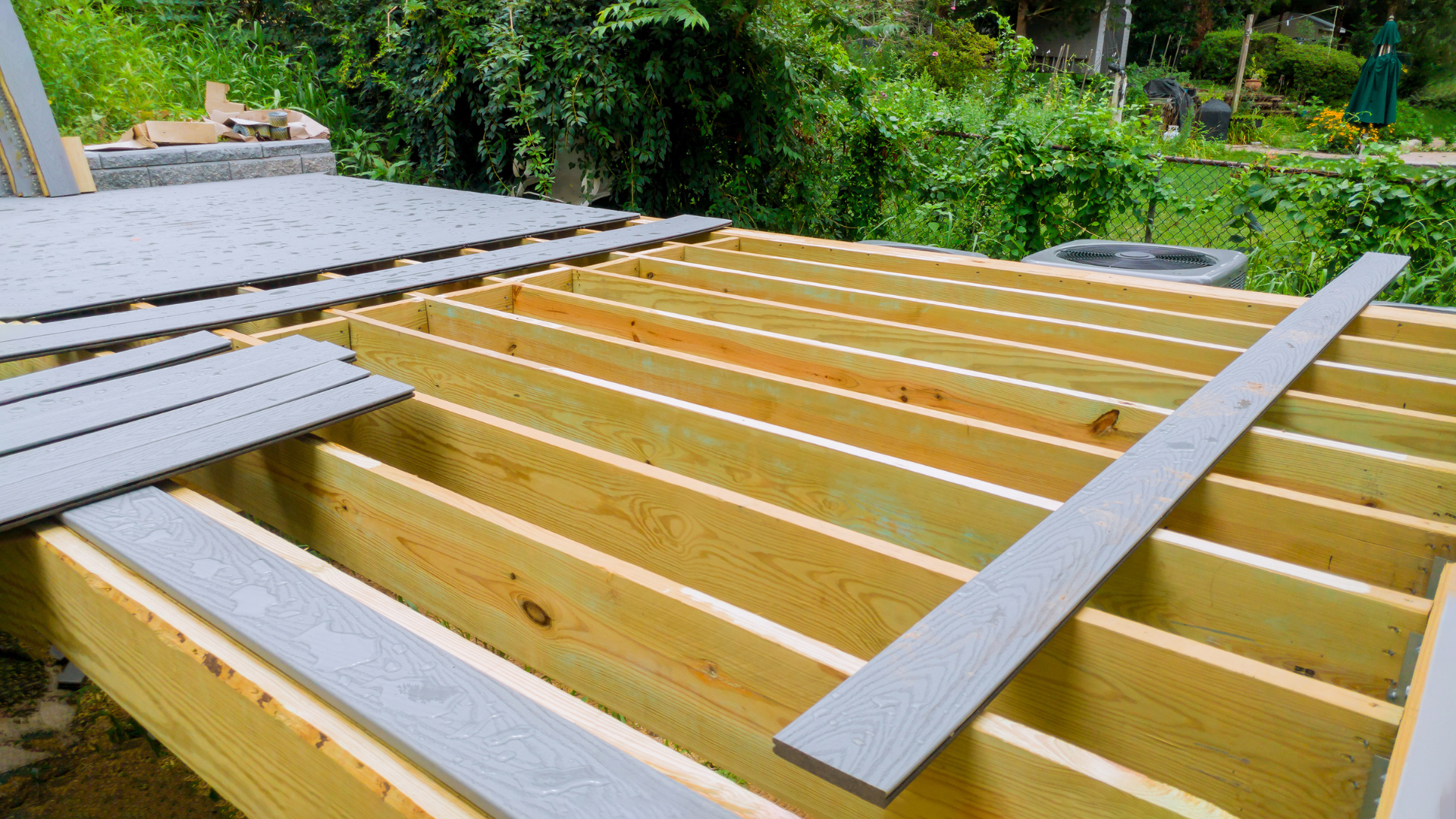 A wooden deck under construction with a roof in the background.