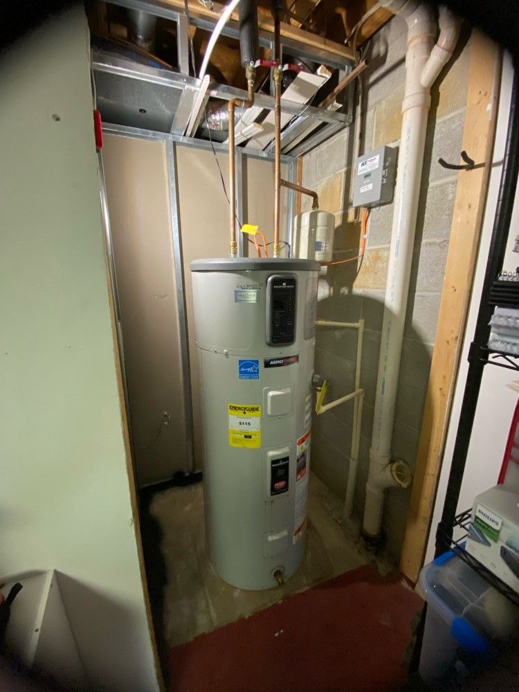 A water heater is sitting in a corner of a room.