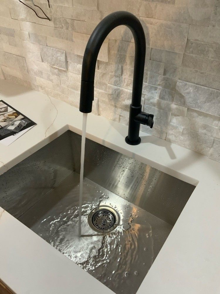 A stainless steel kitchen sink with a black faucet