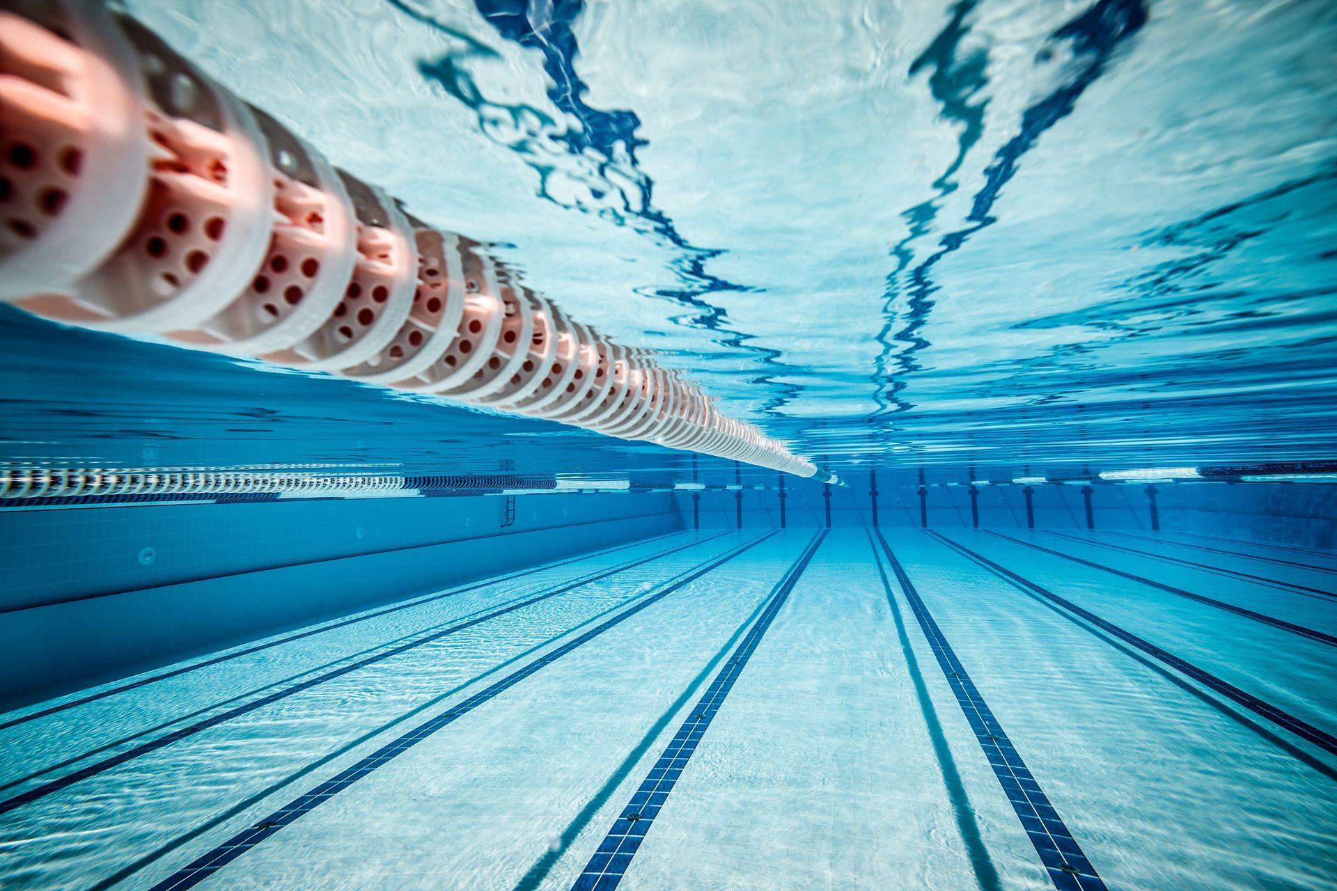 An underwater view of a swimming pool with lane dividers stretching across the crystal blue water.