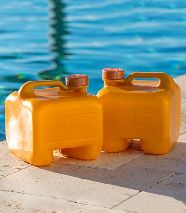Two bright orange, rectangular plastic water jugs sitting on a stone pool deck beside blue water.